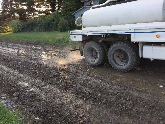 Apply the ROAD-HARD additive with a water truck.