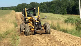 Spread windrowed soil onto the road bed